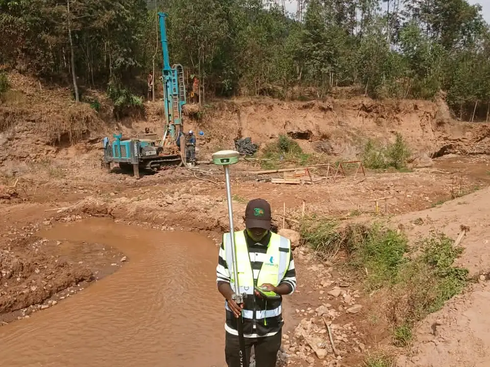 Survey control beside the watercourse, with the drill rig on the far bank